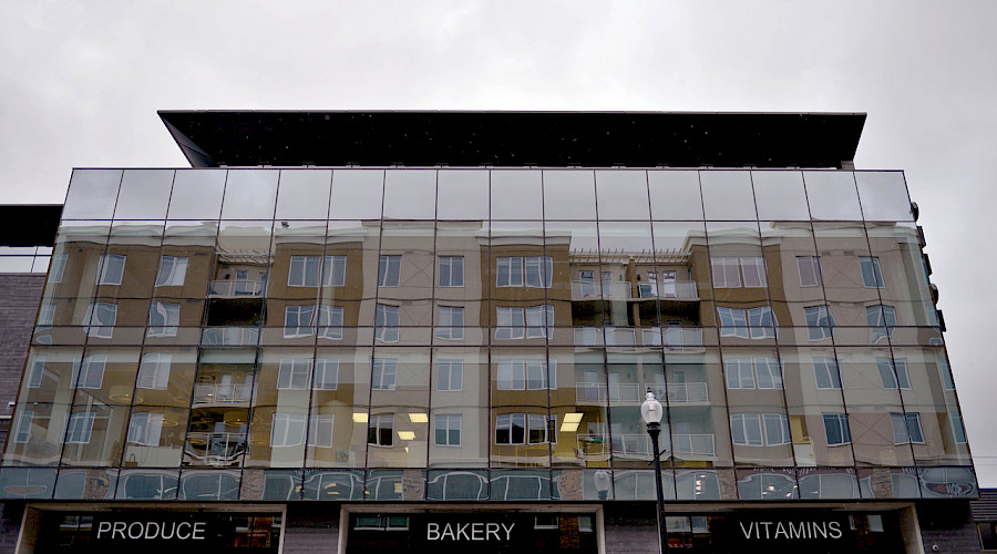 The mirrored exterior of the Odeon commercial property, with signs hanging above the entrance in front of a cloudy grey sky.