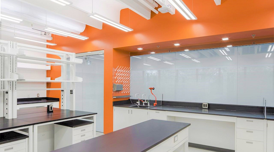 A photo of a clean laboratory classroom with bright lights and an orange accent wall.