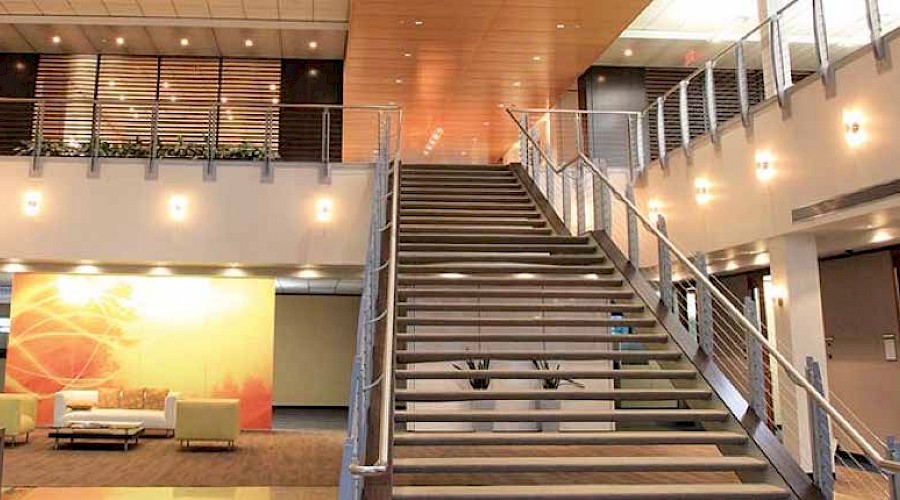 A large staircase in a large, bright room with a seating area to the left.