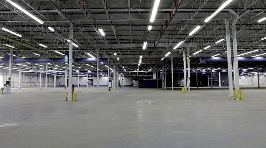A large, open garage lit up by strips of lights on the ceiling.