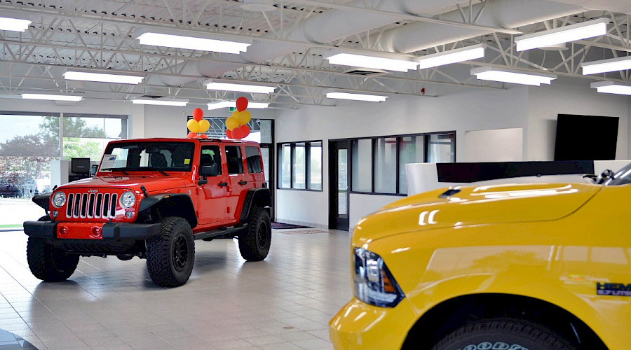 A bright red Jeep wrangler and the front tire of a bright yellow Dodge Ram inside the Courtesy Chrysler building.