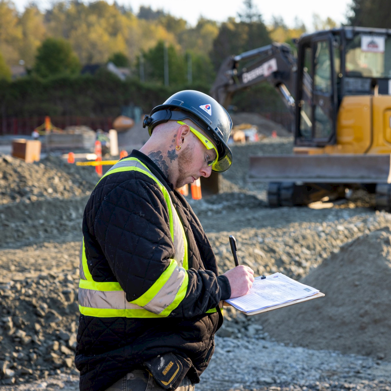 Two Chandos employees sit in an onsite office meeting space with a laptop in their safety gear.