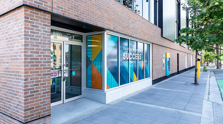 Exterior image of the new Canadian Western Bank in Lethbridge Alberta, built by Chandos Construction Calgary. Window features CWB Branding with yellow, blue, teal, and orange triangles and chevrons.